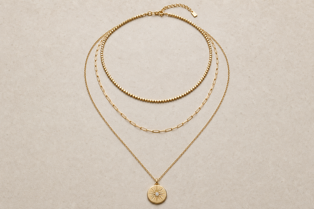 Three necklaces arranged in layers from short to long on a neutral surface