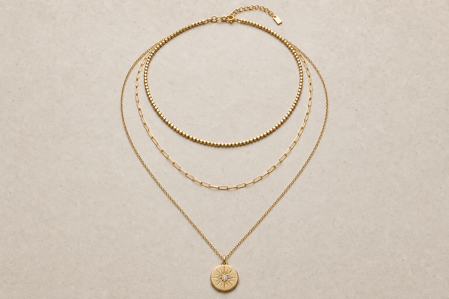 Three necklaces arranged in layers from short to long on a neutral surface